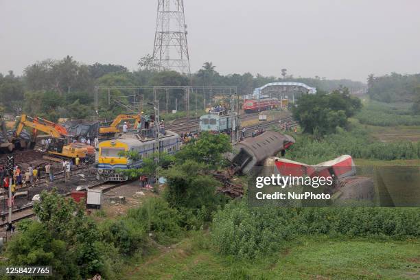 Railway workers and NDRF people are seen at the Coromandel express train accident site as they are busy in the derailed coaches removing work and...