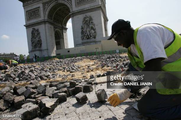 Un ouvrier travaille au pied de l'Arc de Triomphe, le 27 juillet 2004 Place de l'Etoile à Paris, où la chaussée pavée est en cours de rénovation.