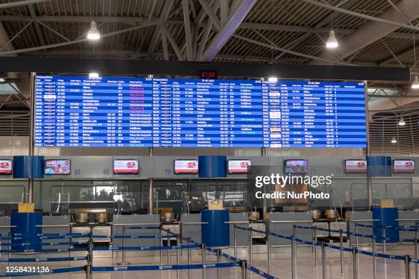 Passenger holding baggage are seen walking in front of the departure screen board and the check-in counters, pulling their luggage. People who travel...