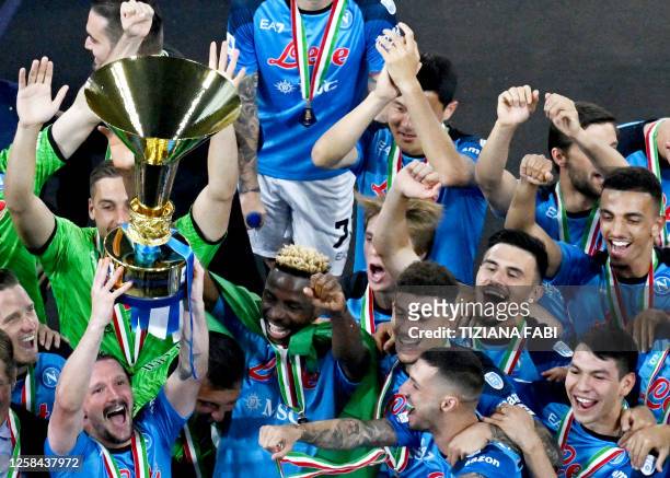 Napoli's Portuguese defender Mario Rui holds the Italian Scudetto Championship trophy as he ans his teammates celebrate winning the 2023 Scudetto...