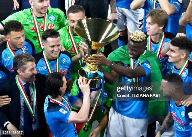 Napoli's Nigerian forward Victor Osimhen holds the Italian Scudetto Championship trophy as he and his teammates celebrate winning the 2023 Scudetto...