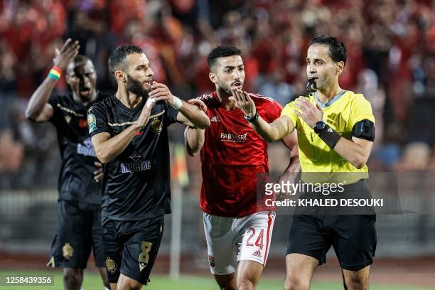 Wydad's Moroccan midfielder Reda Jaadi and Ahly's Egyptian defender Mohamed Abdelmonem speak with Libyan match referee Mutaz Ibrahim during the...