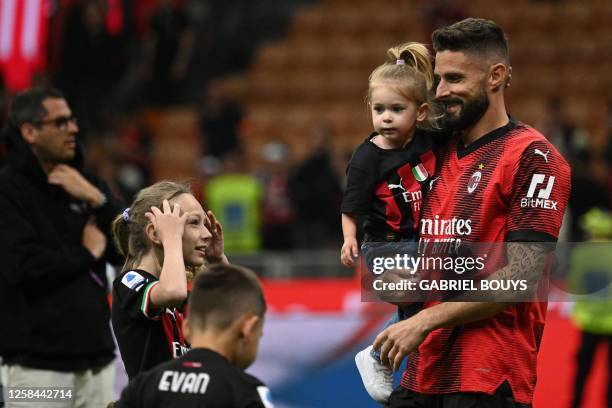 Milan's French forward Olivier Giroud, holding his daughter Aria, walks the pitch with his other children Jade and Evan at the end of the Italian...