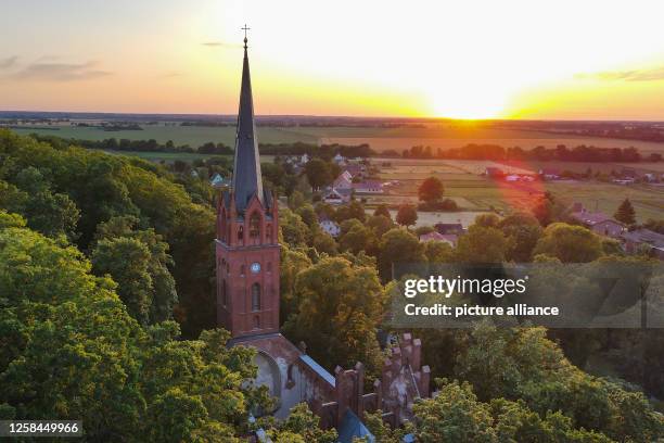 June 2023, Brandenburg, Reitwein: The church of Reitwein in the sunset . The church without a roof is idyllically situated between the trees on the...