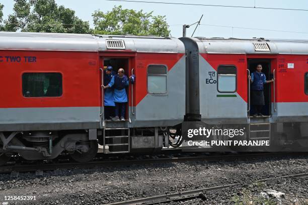 Railway attendants look out from the carriages of a long-distance train as it runs on the newly restored track at the accident site of a recent...