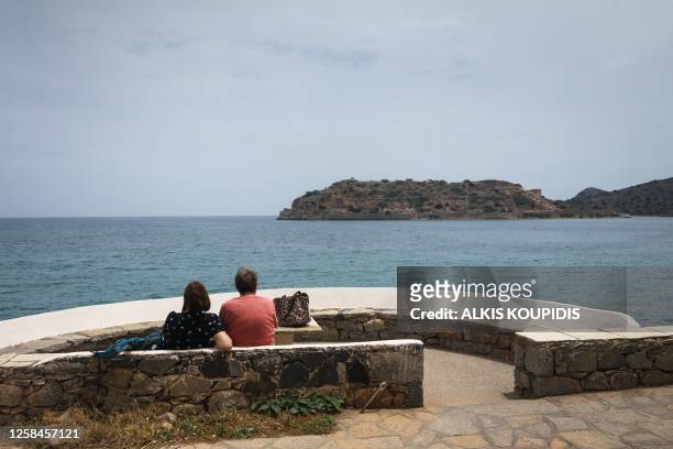 Couple gazes at the island of Spinalonga from the Elounda, Crete island, Greece on May 31, 2023.