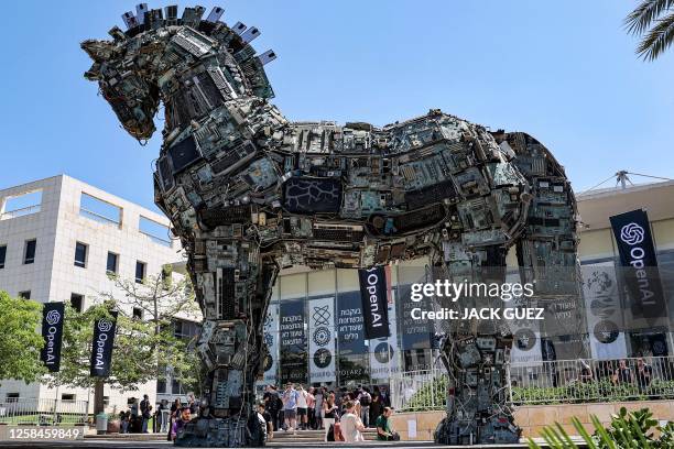 Banners of US artificial intelligence company OpenAI fly near an installation depicting the legendary "Trojan horse" built entirely out of...