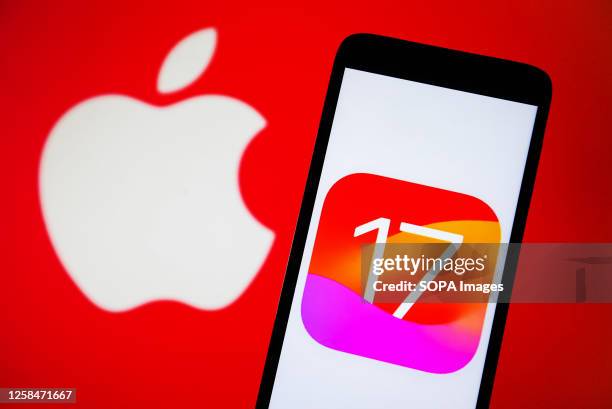 In this photo illustration, iOS 17 logo is seen on a smartphone and Apple logo on a pc screen.