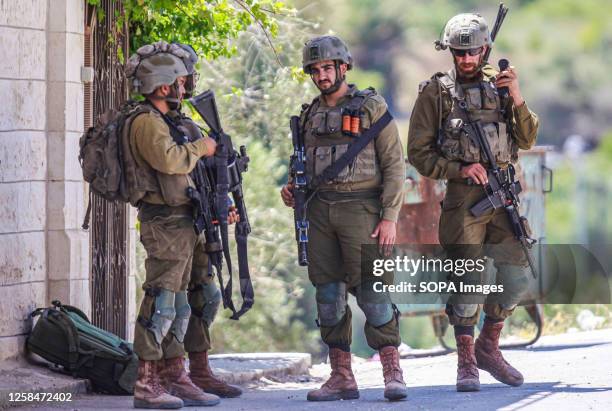 Israeli soldiers stand alert at a random checkpoint in the Palestinian village of Burqa after Jewish settlers from Homesh settlement attacked this...