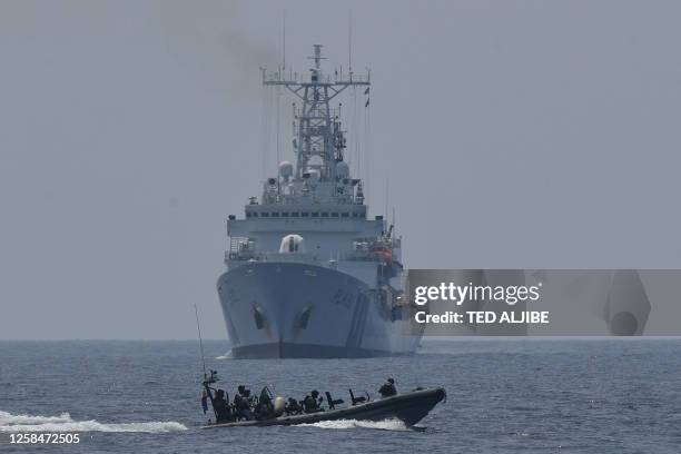 Philippine coast guard personnel aboard a rigid hull boat speed past the Japanese coast guard ship Akitsushima during a maritime exercise with Japan...