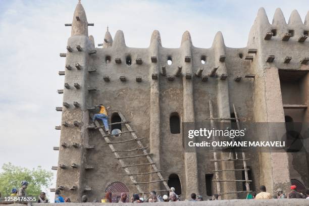 Men climb up ladders as they re-plaster the Great Mosque of Djenne in central Mali on June 4, 2023. Thousand of people from Djenne gather each year...