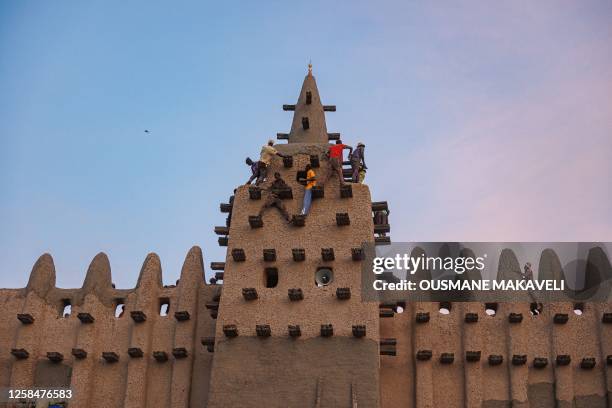 Men climb to re-plaster the Great Mosque of Djenne in central Mali on June 4, 2023. Thousand of people from Djenne gather each year to re-plaster the...
