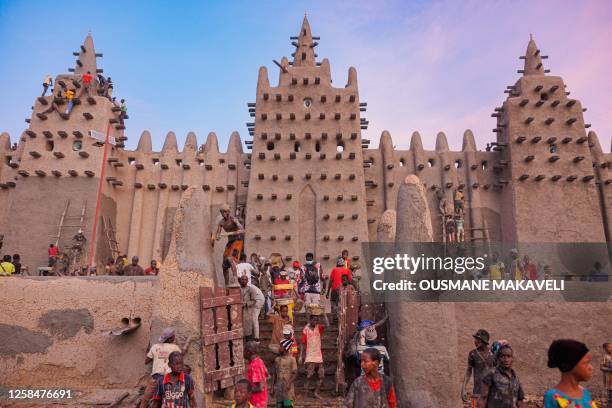 People help re-plastering the Great Mosque of Djenne in central Mali on June 4, 2023. Thousand of people from Djenne gather each year to re-plaster...