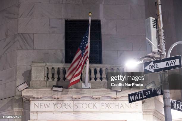 Night view of the illuminated exterior of New York Stock Exchange with American flags. NYSE building has the style of classical architecture of...