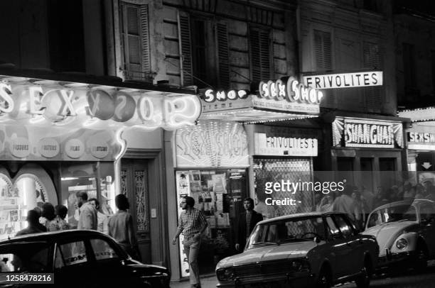 Passers-by look at the windows of sex shops by night, on August 26, 1973 in the Pigalle district of Paris.