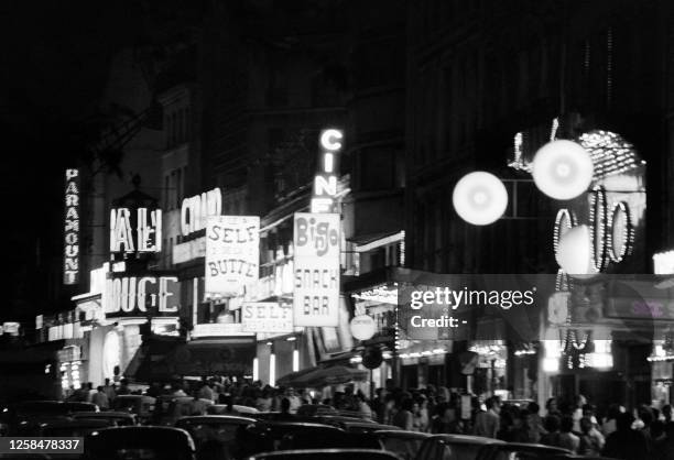 Passers-by look at the windows of sex shops by night, on August 26, 1973 in the Pigalle district of Paris.