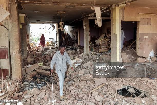 People walk through the rubble as they inspect a house that was hit by an artillery shell in the Azhari district in the south of Khartoum on June 6,...