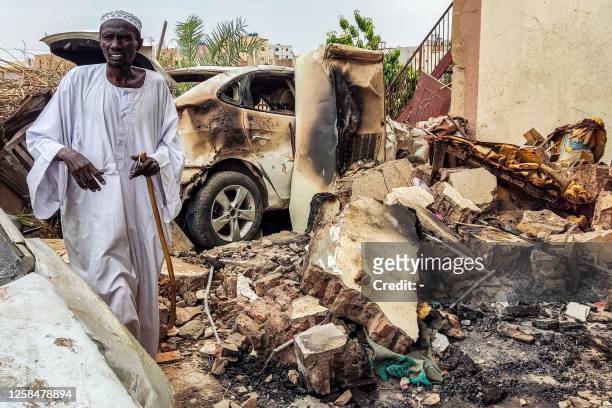 Man inspects damage as he walks through the rubble by a destroyed car outside a house that was hit by an artillery shell in the Azhari district in...