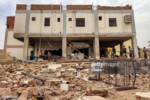 People inspect the rubble at a house that was hit by an artillery shell in the Azhari district in the south of Khartoum on June 6, 2023. The United...