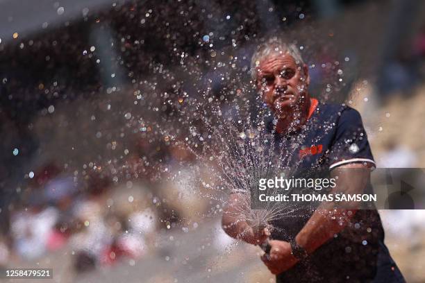 Staff member waters the clay court during the women's singles quarter final match on day ten of the Roland-Garros Open tennis tournament at the Court...