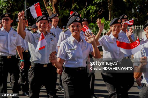Members of the Singapore Navy delegation wave to spectators as they take part the parade of the 2023 Multilateral Naval Exercise Komodo in Makassar...