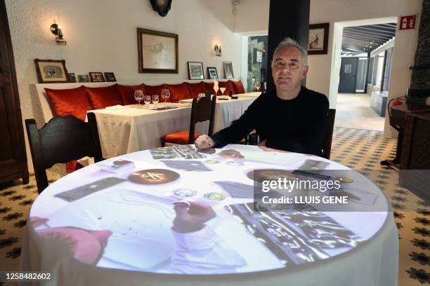 Spanish chef Ferran Adria poses sitting at a table with video projections in the former dining room of the El Bulli restaurant transformed into...