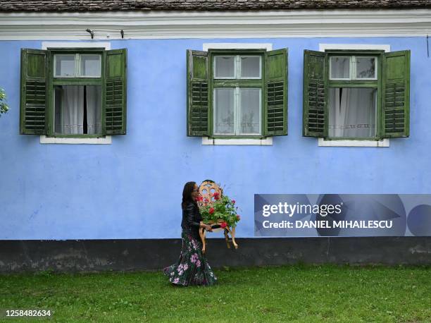 Woman carries flowers in front of the residence of Britain's King Charles III prior to his arrival in Viscri village, central Transylvania region of...