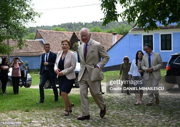 Britain's King Charles chats Caroline Fernolend, chair person of "Mihai Eminescu Trust" NGO as they exit the fortified evangelical church in Viscri...