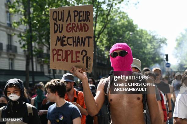 Hooded protester holds a sign saying " who's afraid of the big bad people? " during the 14th day of action after the government pushed a pensions...