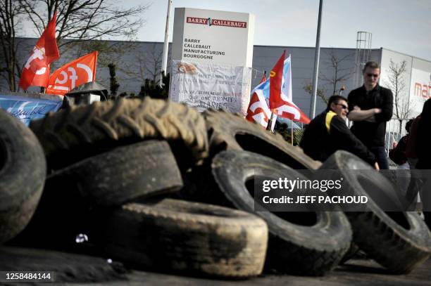 Des employés se tiennent à côté des barricades installées à l'entrée de l'usine de chocolat de Barry Callebaut, le 9 avril 2009 à Dijon, lors du...