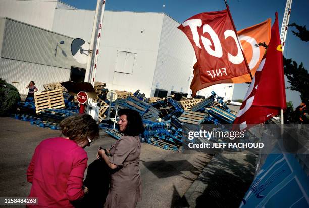 Des personnes se tiennent à côté des barricades installées à l'entrée de l'usine de chocolat de Barry Callebaut, le 9 avril 2009 à Dijon, lors du...