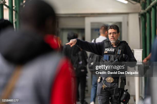 An ICE agent monitors hundreds of asylum seekers being processed upon entering the Jacob K. Javits Federal Building on June 6, 2023 in New York City....