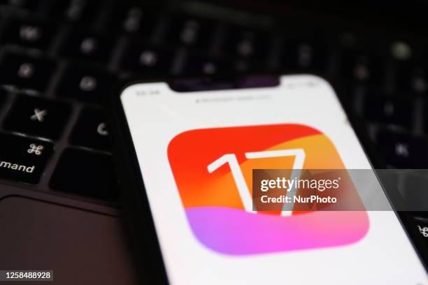 Laptop keyboard and Apple iOS 17 logo on a website displayed on a phone screen are seen in this illustration photo taken in Krakow, Poland on June 6,...