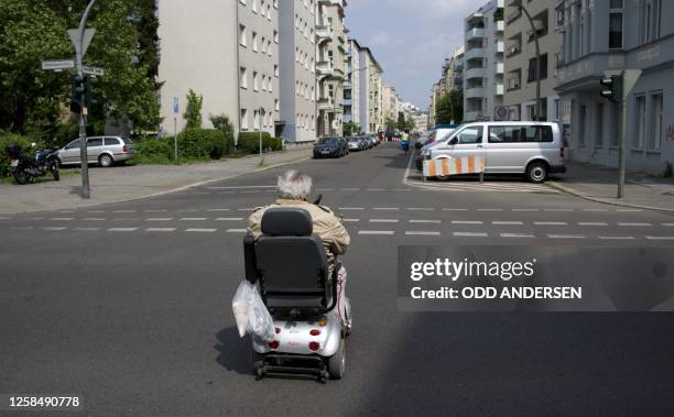 An elderly man crosses an intersection on his mobility scooter in central Berlin on May 18, 2011. AFP PHOTO / ODD ANDERSEN