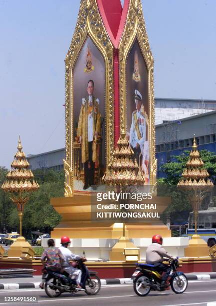 Motorcycles ride past big painted portraits of Thai King Bhumibol Adulyadej 25 March 1999 in Bangkok. Thai people are in a year-long celebration of...