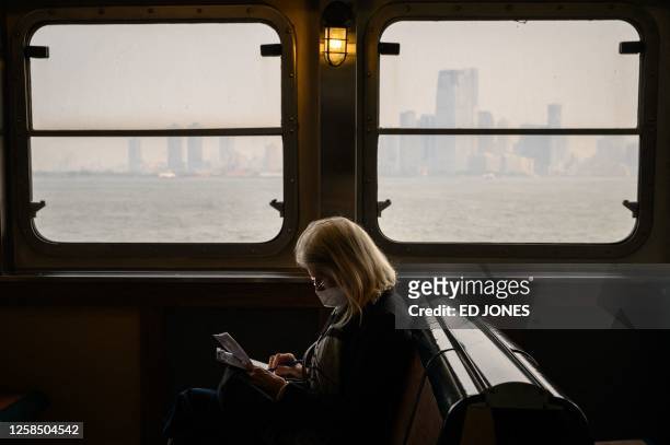 Passenger wearing a face mask rides the Staten Island Ferry past the Manhattan skyline during heavy smog in New York on June 6, 2023. Smoke from...