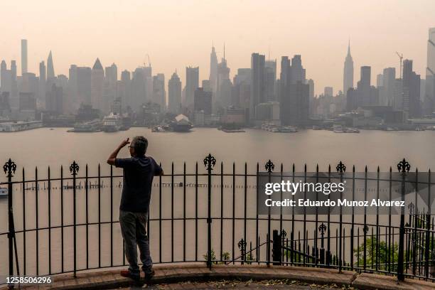 Person looks out at the New York City skyline as its covered with haze and smoke from Canada wildfires on June 7, 2023 in Weehawken, New Jersey. Air...