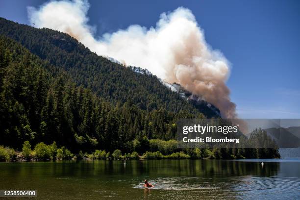 Swimmer in Cameron Lake in front of the Cameron Bluffs wildfire near Port Alberni, British Columbia, Canada, on Tuesday, June 6, 2023. Canada is on...