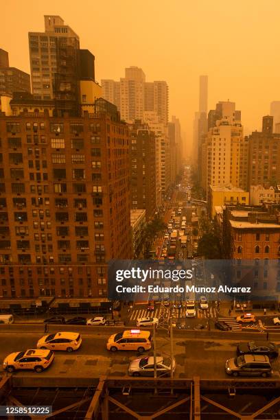 Traffic moves down a city street as smoke from Canadian wildfires casts a haze over the area on June 7, 2023 in New York City. Air pollution alerts...