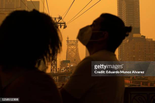 People wear masks as smoke from Canadian wildfires casts a haze over the area on June 7, 2023 in New York City. Air pollution alerts were issued...