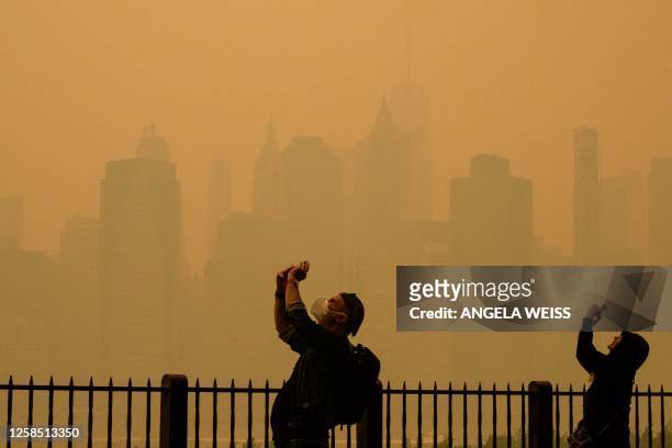 People take photos of the sun as smoke from the wildfires in Canada cause hazy conditions in New York City on June 7, 2023. Smoke from Canada's...