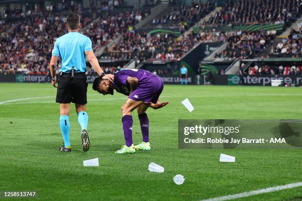 Nicolas Gonzalez of Fiorentina removes plastic pint glasses from the pitch after they were thrown by West Ham United fans at Cristiano Biraghi of...