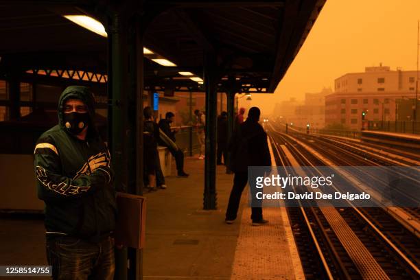 Person waiting for the subway wears a filtered mask as smoky haze from wildfires in Canada blankets a neighborhood on June 7, 2023 in the Bronx...