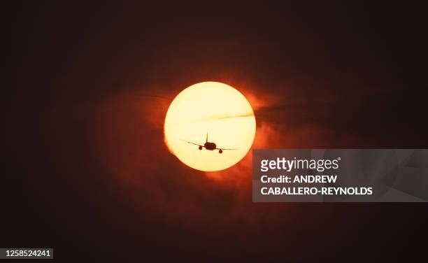 Plane passes in front of the sun on a hazy evening as smoke from wildfires in Canada cause hazy conditions in Washington, DC, on June 7, 2023. A Code...