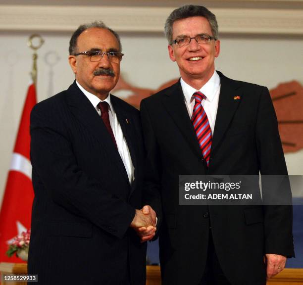 German Interior Minister Thomas de Maiziere shakes hands with his Turkish counterpart Besir Atalay during a press conference in Ankara on September...