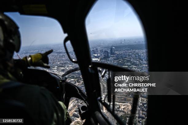 Pilot of a French army Fennec helicopter points at the Paris skyline with the La Defense business district, the Eiffel tower and the Montparnasse...