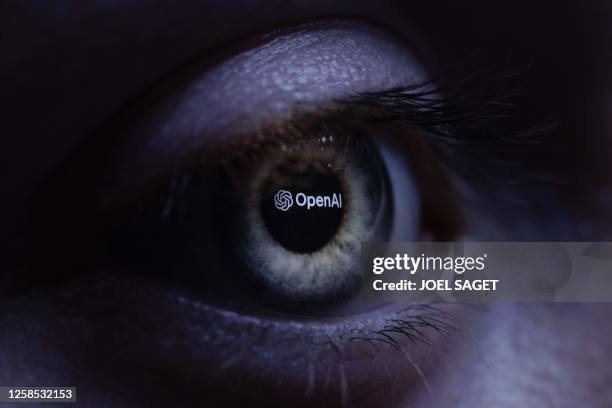 This illustration photograph taken with a macro lens shows an 'OpenAI' logo reverse projected onto a human eye at a studio in Paris on June 6, 2023....