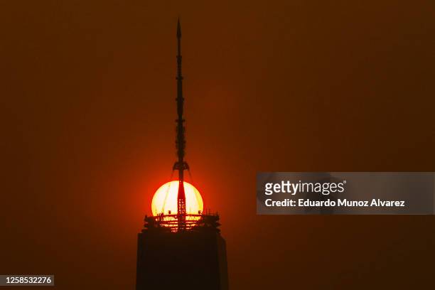 The sun rises behind the One World Trade Center, while the smoke from Canada wildfires covers the Manhattan borough as it is seen from Liberty State...