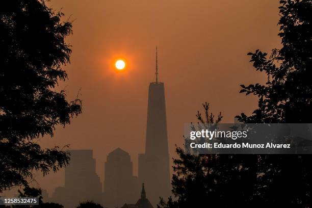 The sun rises behind the One World Trade Center in New York, while the smoke from Canada wildfires covers the Manhattan borough as it is seen from...