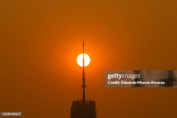 The sun rises behind the One World Trade Center in New York, while the smoke from Canada wildfires covers the Manhattan borough as it is seen from...